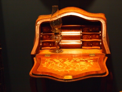 [Flip-top desk with top down showing in the inlay on the writing surface and the multiple, small drawers inside the desk.]